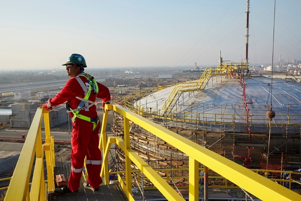 A Petrofac worker standing on metal scaffolding at a work site.